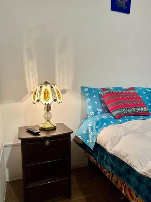 a lamp on a night stand next to a bed at Posada Escondida in Cusco