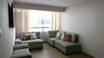 a living room with two chairs and a couch and a window at Tu mejor opción Departamento Familiar in Lima