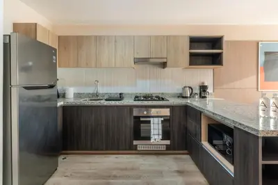a kitchen with wooden cabinets and a stainless steel refrigerator at Miraflores Modern Apartments Benavides by Geko in Lima