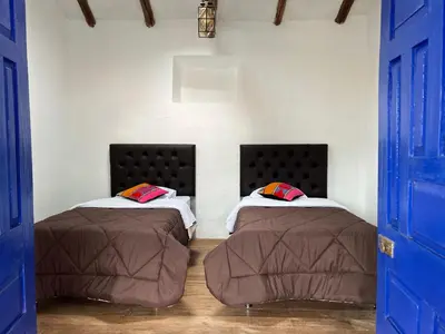 two beds in a room with blue doors at Auquis Hostel in Cusco