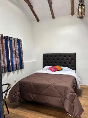 a bed with a black headboard in a room at Auquis Hostel in Cusco