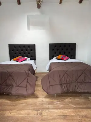 two beds sitting next to each other in a room at Auquis Hostel in Cusco