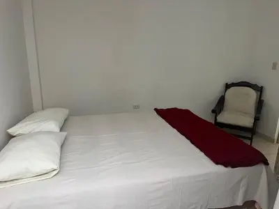 a white bed with a red blanket on top of it at Punta Hermosa - depa Santa Cruz in Punta Hermosa