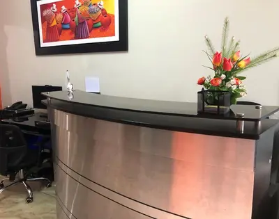 a reception desk in an office with a vase of flowers at B&B Cusing Wasi in Lima