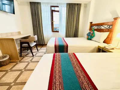 a hotel room with two beds and a desk at Hotel Rojas Machupicchu in Machu Picchu