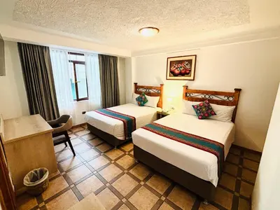 a hotel room with two beds and a desk at Hotel Rojas Machupicchu in Machu Picchu