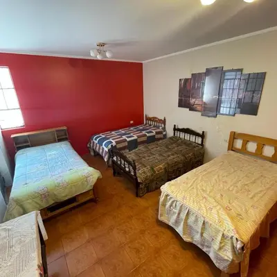 a room with three beds and a red wall at Habitación para 4 personas a pasos de la plaza de armas in Ayacucho
