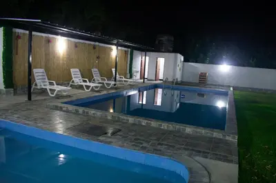 a swimming pool at night with chairs around it at Kampu Wasi - Casa de Campo in Pachacamac