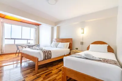 a hotel room with two beds and a table at Hostal Cusco Guest Home in Cusco
