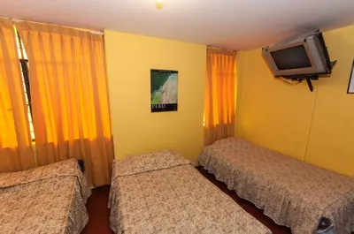 a hotel room with two beds and a tv at Hostal Iquique in Lima