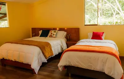 two beds in a room with yellow walls at Ecoterra Inka Lodge in Quillabamba