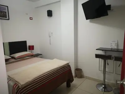 a small bedroom with a bed and a sink at Hostal Onassis in Lima
