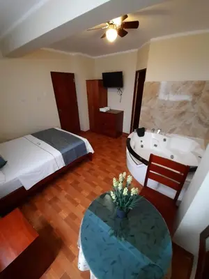 a bedroom with a bed and a bath tub and a table at Hotel Wismont Piñales in La Merced