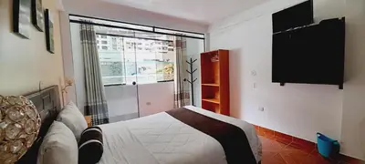 a bedroom with a bed and a large window at El Tambo Machupicchu in Machu Picchu