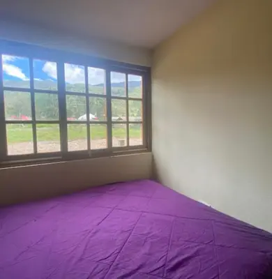 a bedroom with a purple bed and a window at Casa de campo Miraflores in Oxapampa