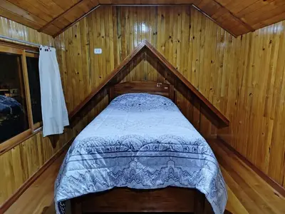 a bedroom with a bed in a wooden cabin at Casa de Machi in Villa Rica