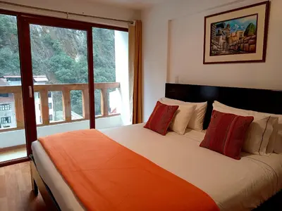 a bedroom with a large bed with red pillows at El Quetzal MachuPicchu in Machu Picchu