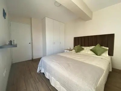 a bedroom with a large white bed with green pillows at Hermoso departamento estreno céntrico in Lima