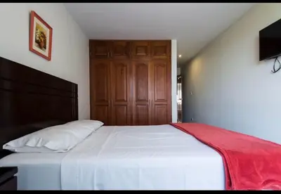a bedroom with a white bed with a wooden door at Apartamento en Miraflores in Lima