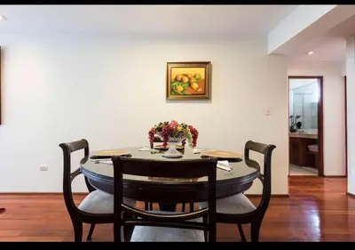 a dining room table with two chairs and a painting on the wall at Apartamento en Miraflores in Lima