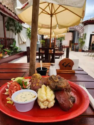 a plate of food with meat and vegetables on a table at ViaVia Ayacucho in Ayacucho