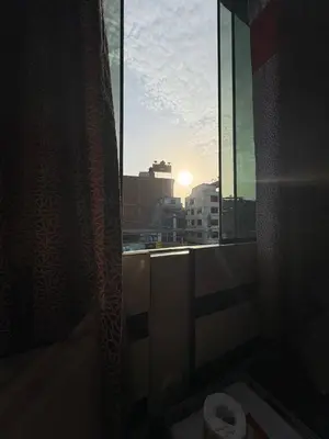 a bathroom with a toilet and a window with the sunset at Hospedaje Winikunka in Lima