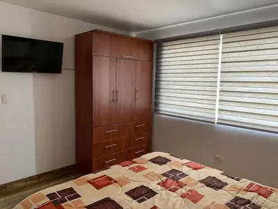 a bedroom with a bed and a dresser and a television at Apartamento Tumi Wasi in Lima