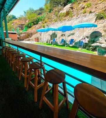 a row of bar stools in front of a swimming pool at Restobar & Hotel Campestre Aisha in Cocachacra