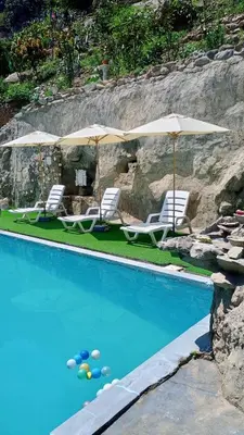 a swimming pool with chairs and umbrellas at Restobar & Hotel Campestre Aisha in Cocachacra