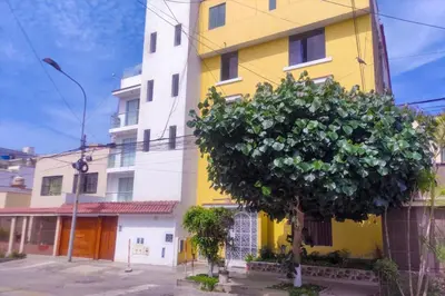 a yellow building with a tree in front of it at Cozy Apartment for Tourist in Lima