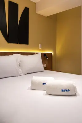 a white bed with two towels on top of it at 28 de Julio by Geko in Lima