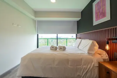 a bedroom with a large white bed with two clocks on it at Plaza 27 by Geko in Lima