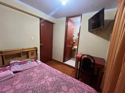 a bedroom with a pink bed and a television at Habitación con baño privado in Ayacucho