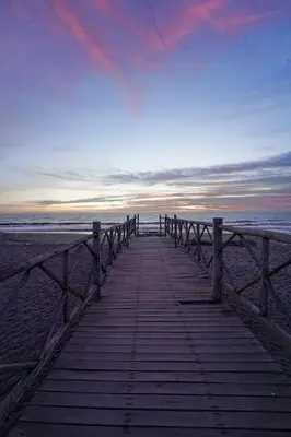 a wooden boardwalk leading to the beach at sunset at Casa de playa en Chincha Baja in Chincha Baja