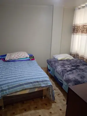 a bedroom with two beds and two windows at Macchi in Ayacucho