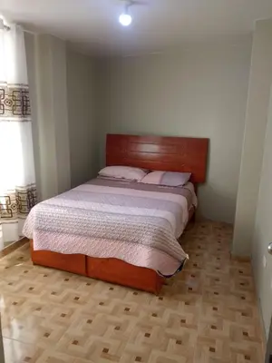 a bedroom with a bed with a wooden headboard at Macchi in Ayacucho