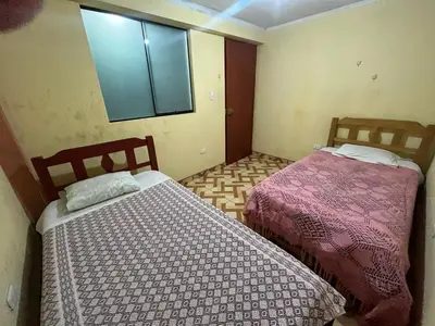 two beds in a small room with a window at Habitación 2 camas in Ayacucho