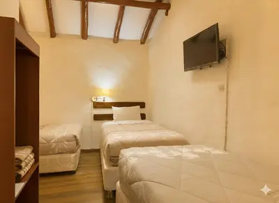 a room with two beds and a flat screen tv at Naty's Guest House in Cusco