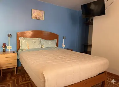 a bedroom with a large bed with a blue wall at Naty's Guest House in Cusco