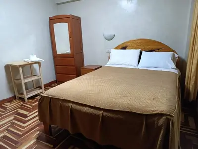 a bedroom with a large bed and a small table at Hostal Lucerito in Cusco