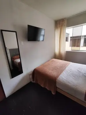 a bedroom with a bed with a mirror and a tv at Habitación acogedora cerca a Larcomar in Lima