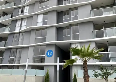 a large apartment building with a palm tree in front of it at Come and have fun with the family in San Bartolo