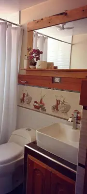 a bathroom with a sink and a toilet and a mirror at La Cabaña de Mary in Oxapampa