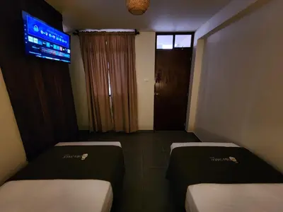 two beds in a room with a tv on the wall at China Chancay Hotel in Chancay