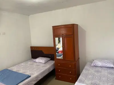 a bedroom with two beds and a dresser and a cabinet at Casa de campo en Chincha in Chincha
