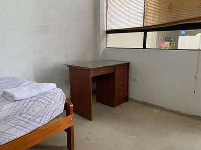 a bedroom with a desk and a bed and a window at Casa de campo en Chincha in Chincha