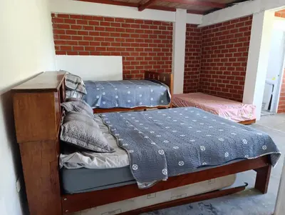 two twin beds in a room with a brick wall at Casa Hospedaje terraza con vista a La Merced in La Merced