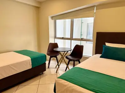 a room with two beds and a table and chairs at Hotel Limamar in Lima