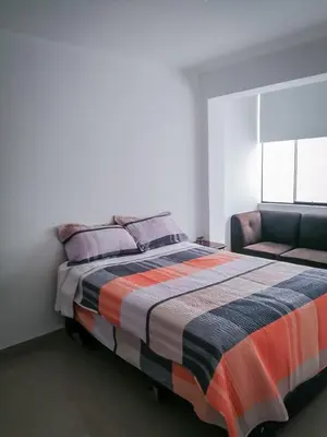 a bedroom with a bed and a couch at Amplio departamento completo cerca al aeropuerto in Lima