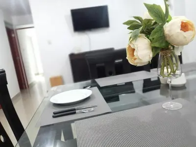 a glass table with a vase with roses in it at Amplio departamento completo cerca al aeropuerto in Lima